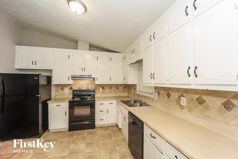 A kitchen with white cabinets and a black refrigerator.