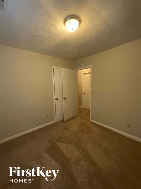 a bedroom with a carpeted floor and a door to a closet