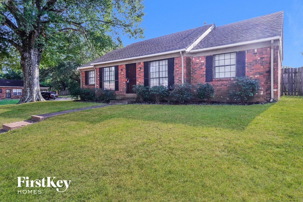 a brick house with a lawn and a tree