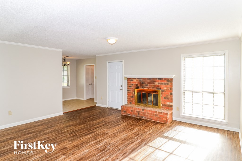 a living room with a brick fireplace and wooden floors