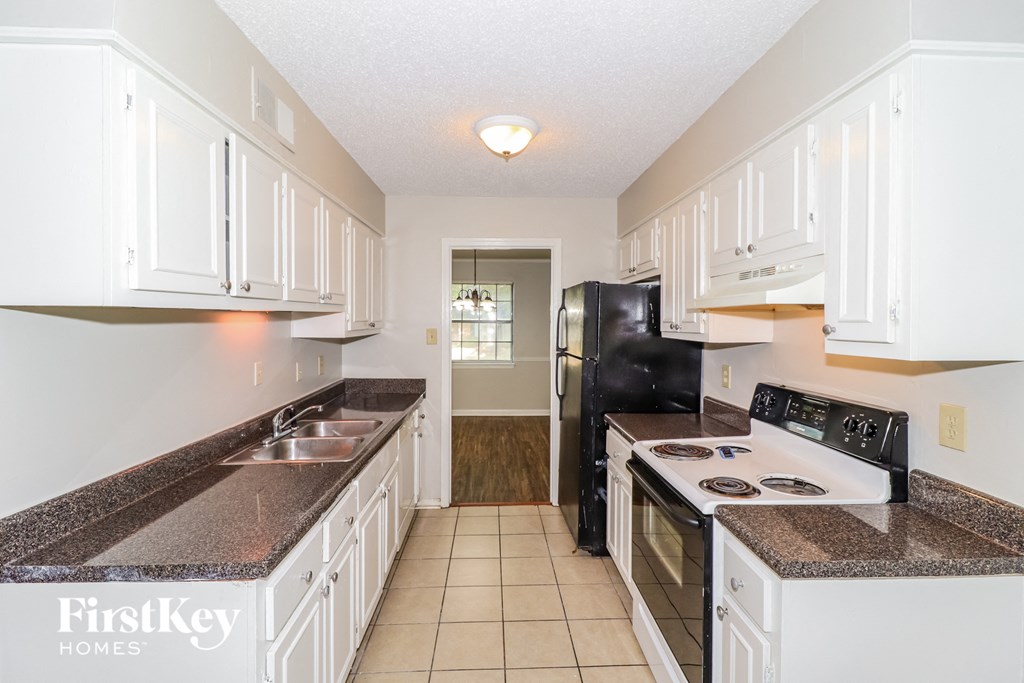 a kitchen with white cabinets and black appliances and white counter tops