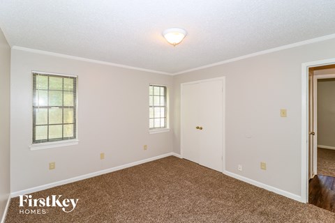 the spacious living room of a house with carpet and a door to the kitchen