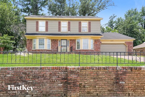 a house with a brick wall and a fence in front of it