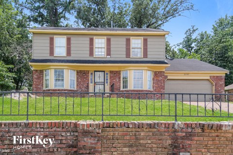 a house with a brick wall and a fence in front of it