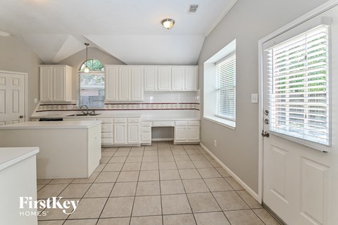 A kitchen with white cabinets and a tiled floor.