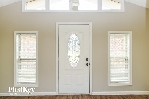 an empty room with a white door and two windows with blinds