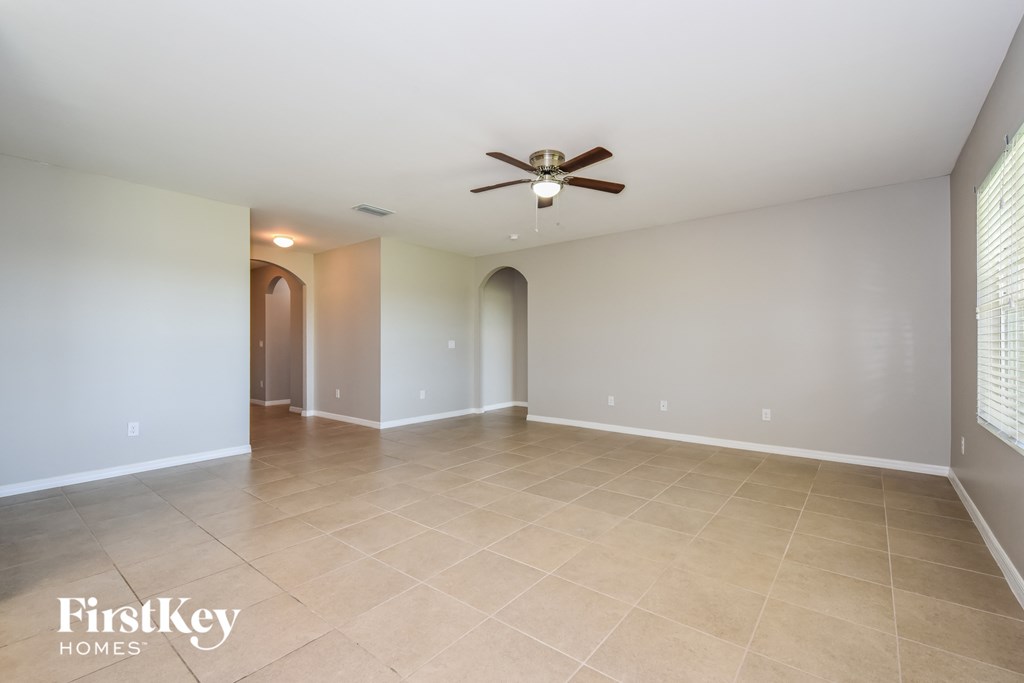 an empty living room with a ceiling fan and tile floor