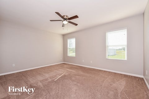 the spacious living room with carpet and ceiling fan
