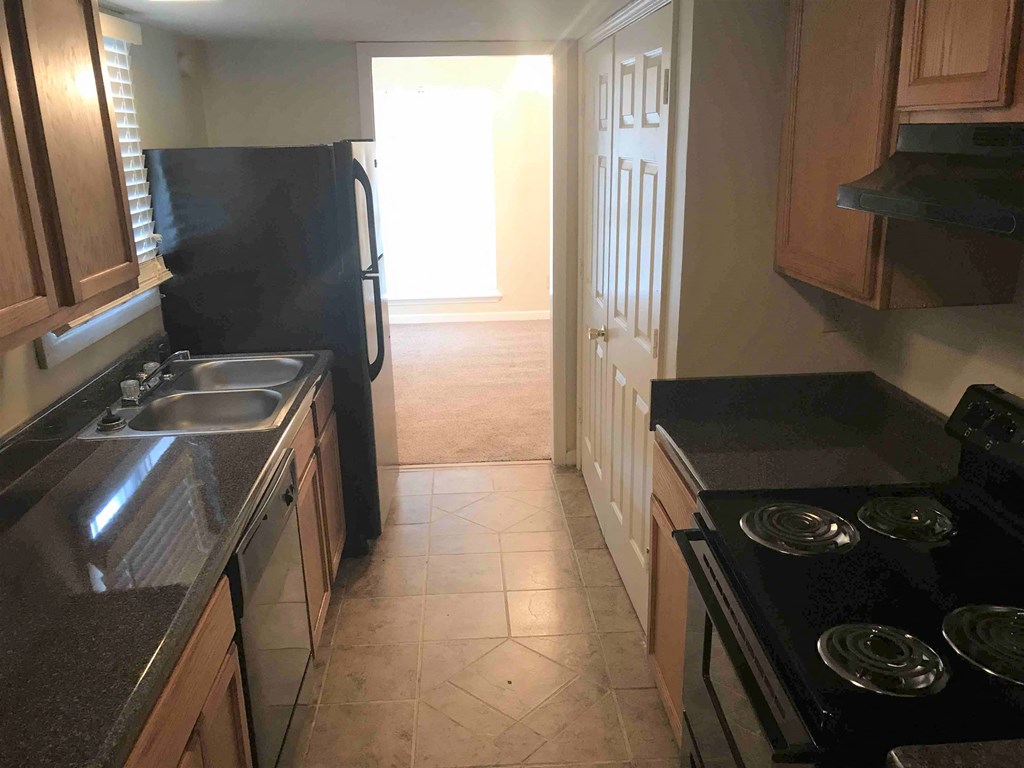 A kitchen with a black refrigerator and a black stove top oven.