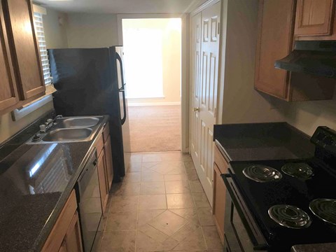A kitchen with a black refrigerator and a black stove top oven.