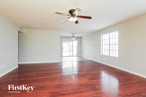 A spacious room with a ceiling fan and wooden flooring.