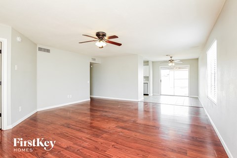 A room with a ceiling fan and wooden flooring.