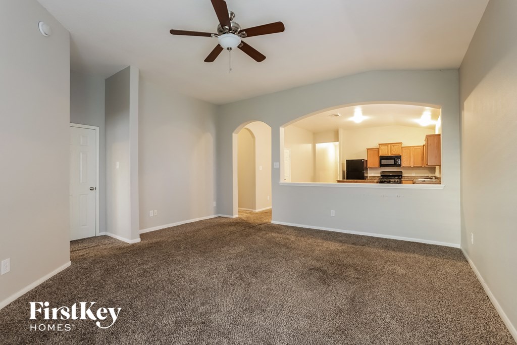 an empty living room with carpet and a ceiling fan