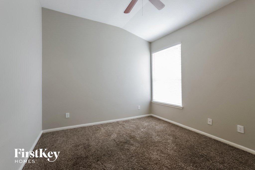 a carpeted room with a window and a ceiling fan