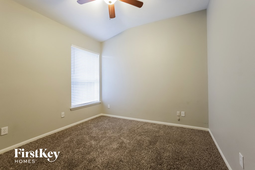 an empty room with a ceiling fan and a window