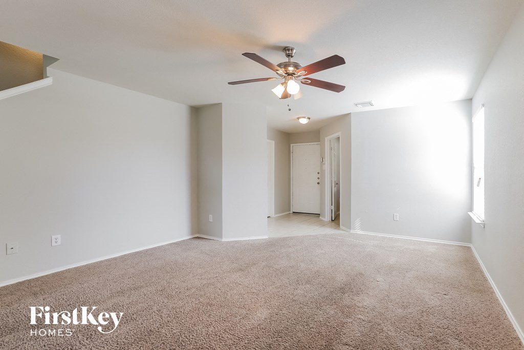 a spacious living room with white walls and a ceiling fan