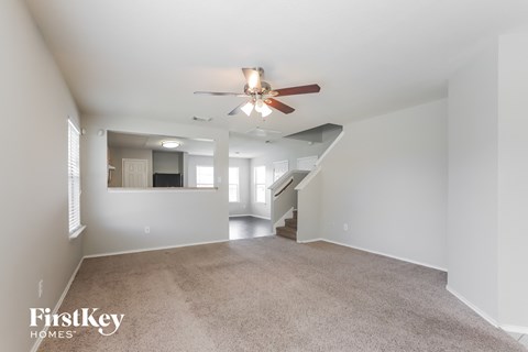a spacious living room with carpet and a ceiling fan