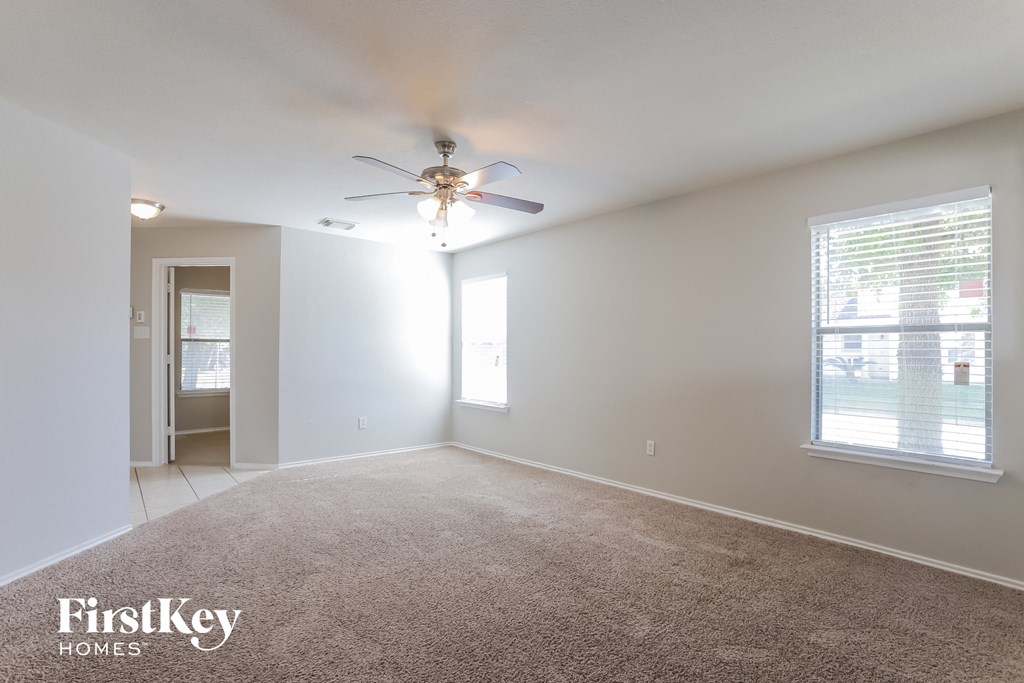 an empty living room with a ceiling fan and a window