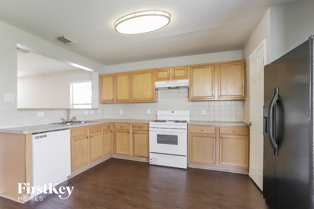 an empty kitchen with wooden cabinets and white appliances