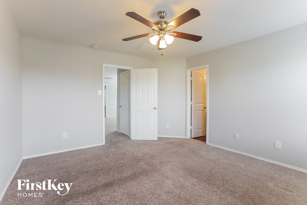 a spacious living room with carpet and a ceiling fan
