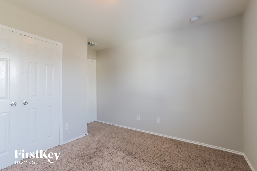 a bedroom with white walls and carpet and a white door