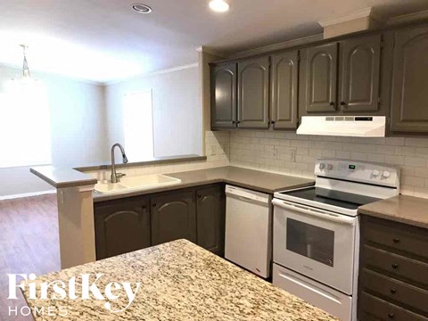 A kitchen with a white stove top oven and white cabinets.