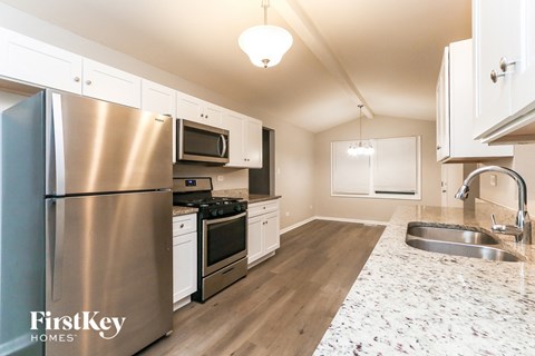 A kitchen with a stainless steel refrigerator and a marble countertop.