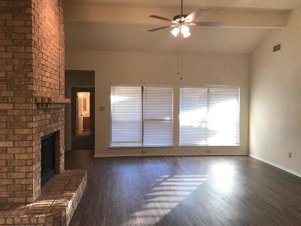 an empty living room with a fireplace and a ceiling fan