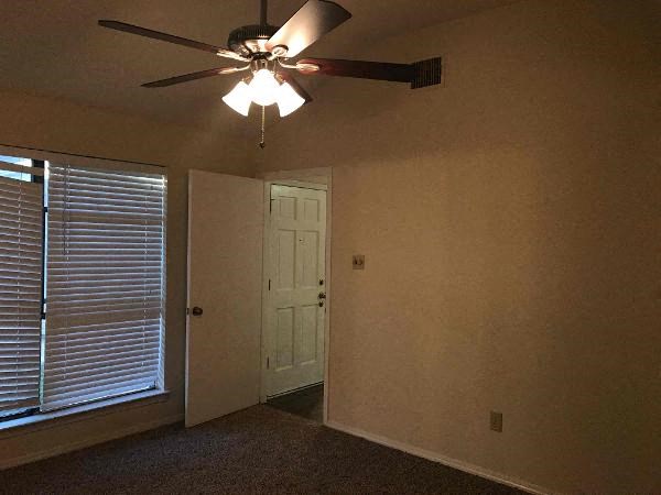 an empty room with a ceiling fan and a door