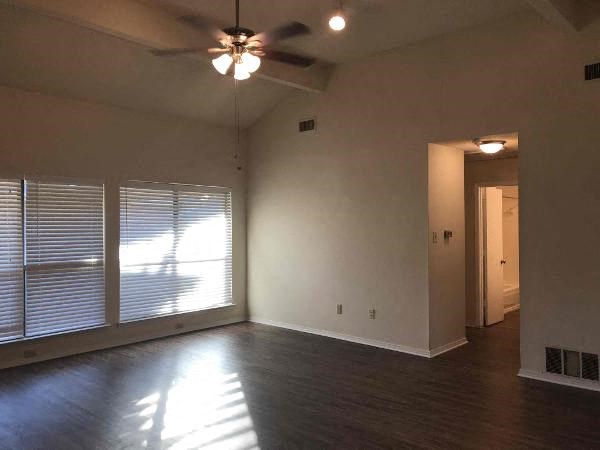 an empty living room with a ceiling fan