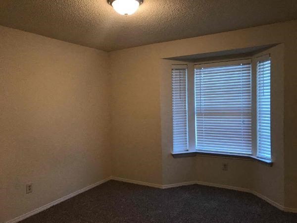 an empty room with a large window and blinds