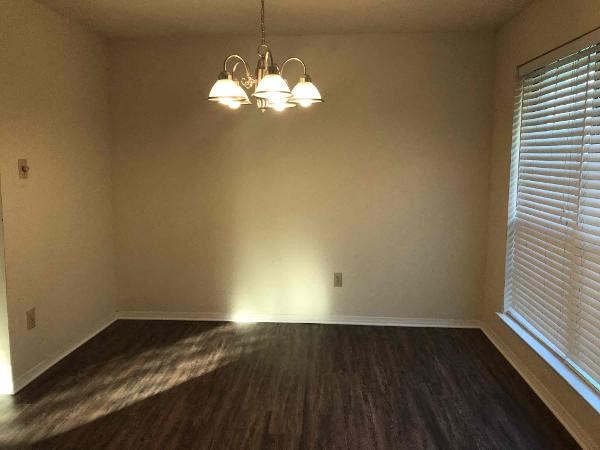 an empty living room with a chandelier and a window
