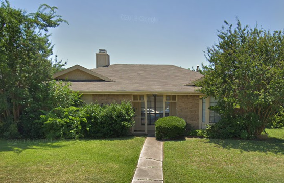 a house with a lawn and trees in front of it
