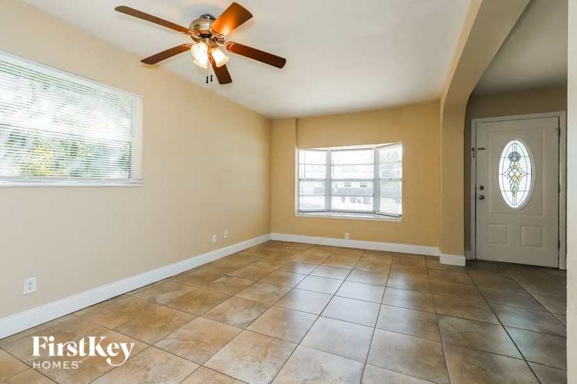 an empty living room with a ceiling fan and a door