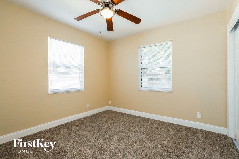 an empty room with a ceiling fan and two windows