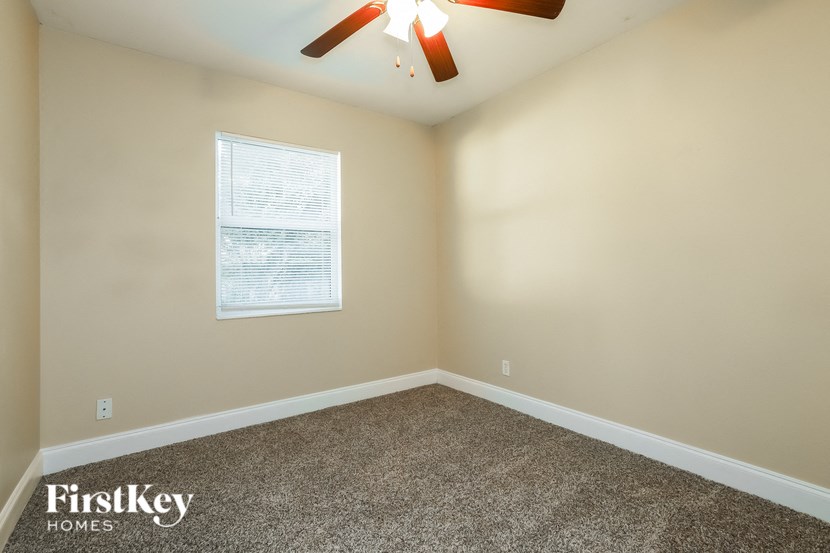 an empty room with a ceiling fan and a window