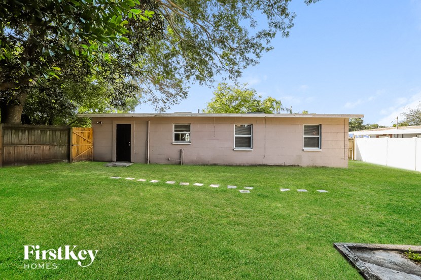a small pink house with a yard and a fence