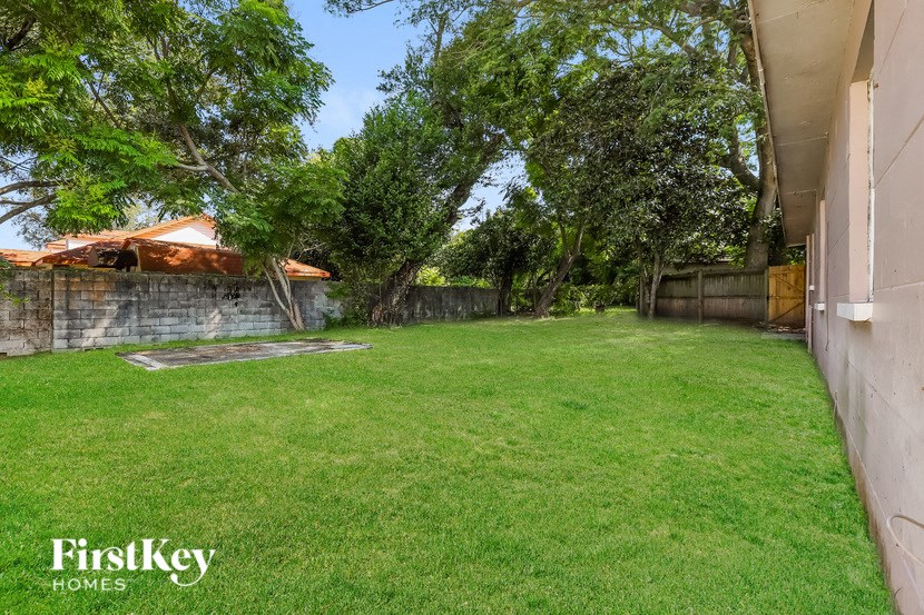 a backyard with green grass and a stone wall