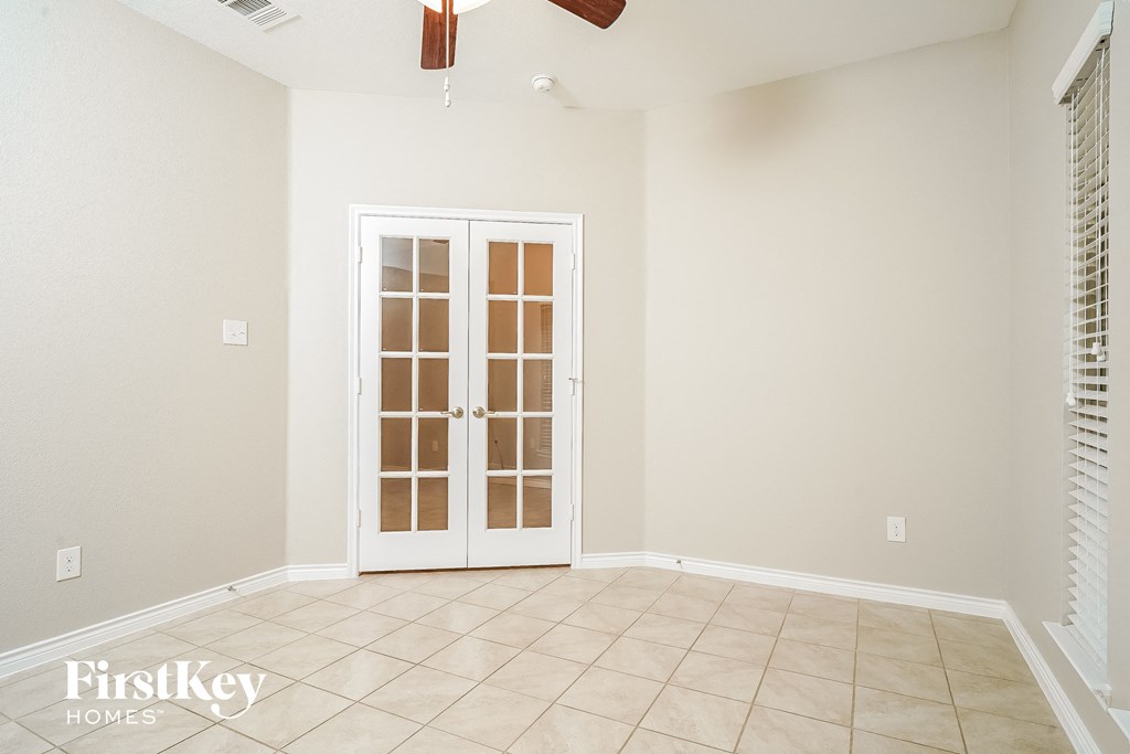 A room with a white door and a ceiling fan.