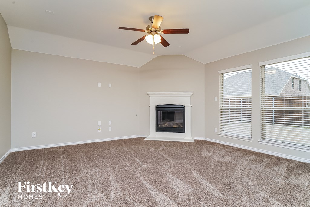 A spacious living room with a fireplace and a ceiling fan.