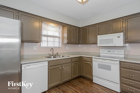 A kitchen with brown cabinets and white appliances.