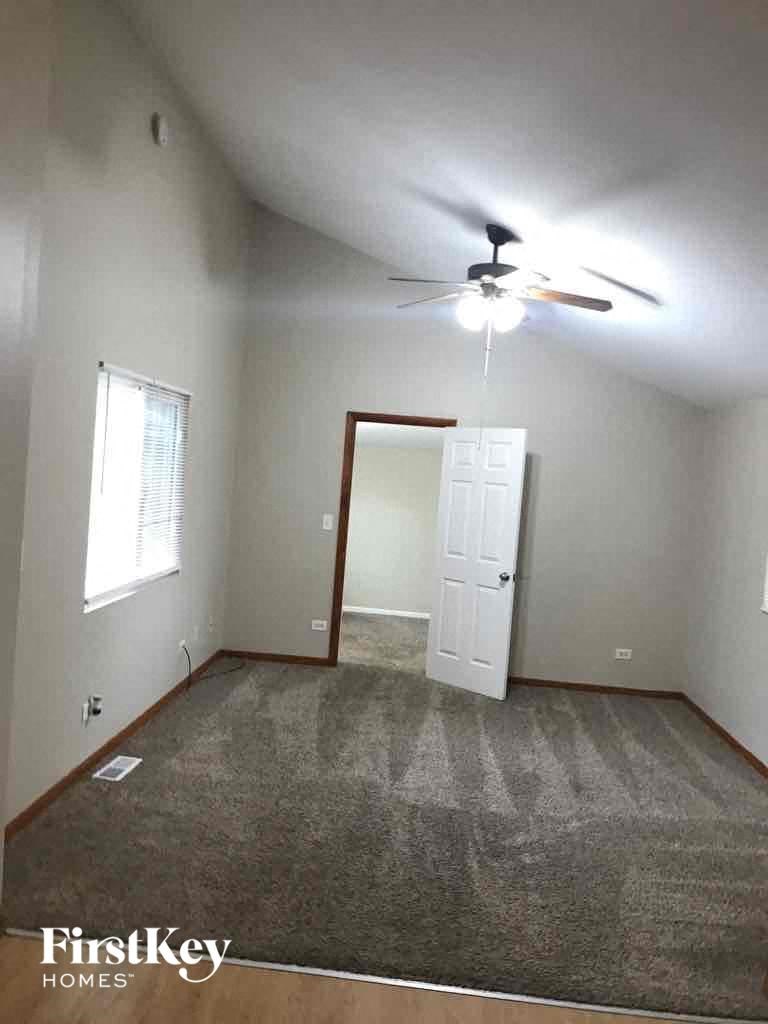 A room with a carpeted floor and a ceiling fan.