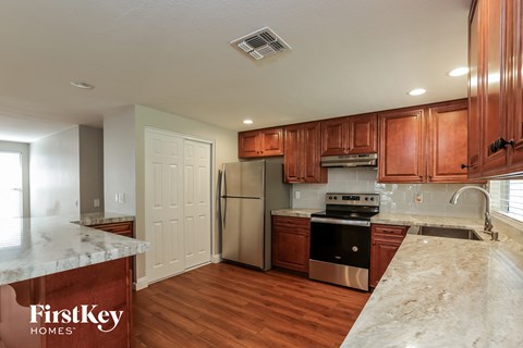 A kitchen with wooden cabinets and a marble countertop.