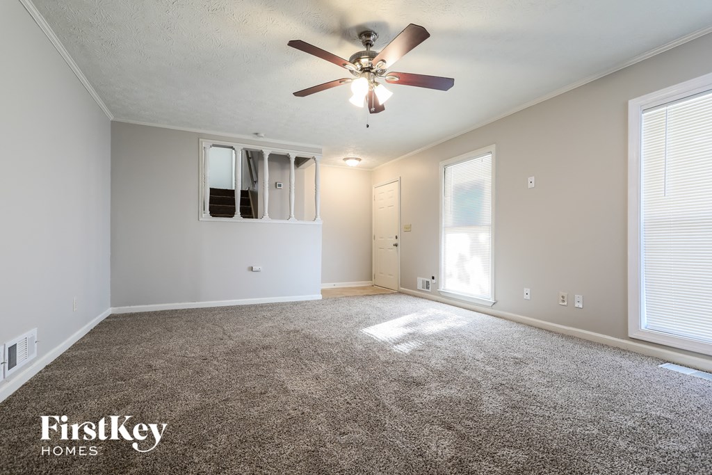 A spacious room with a ceiling fan and carpeted floor.