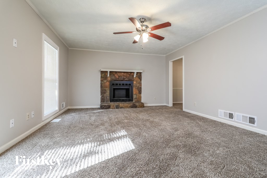 A living room with a fireplace and a ceiling fan.