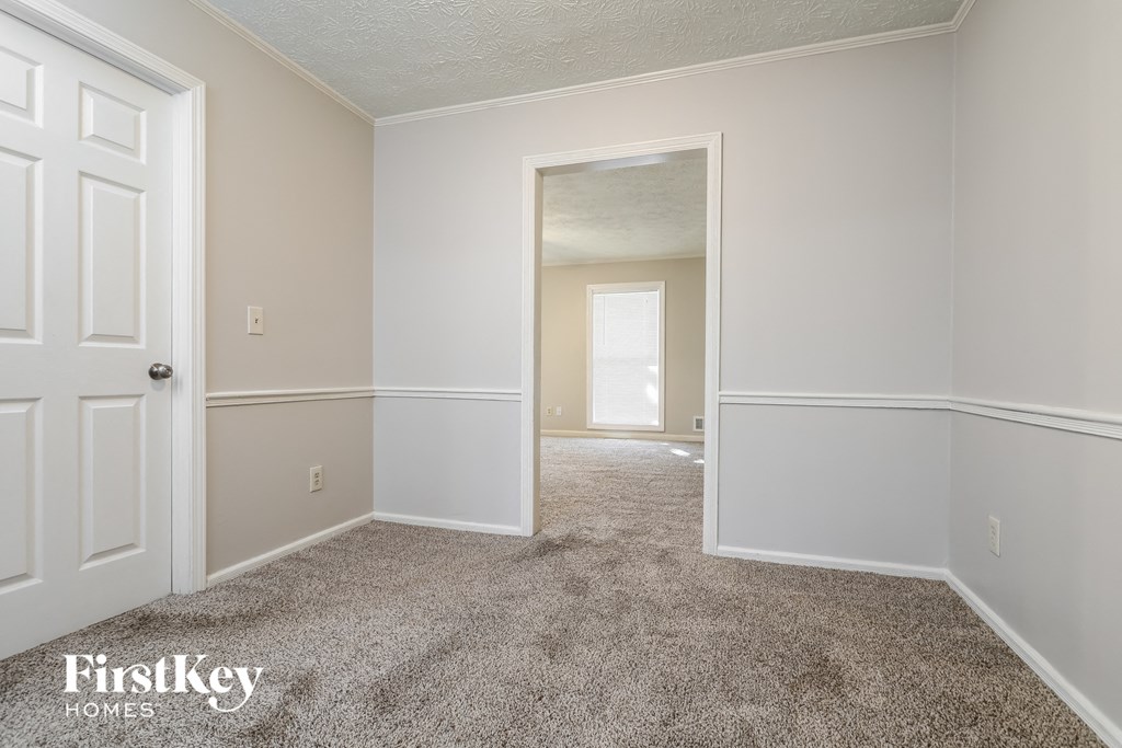 A carpeted room with a door and a window.