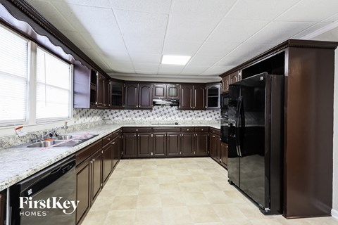 A kitchen with brown cabinets and a black refrigerator.