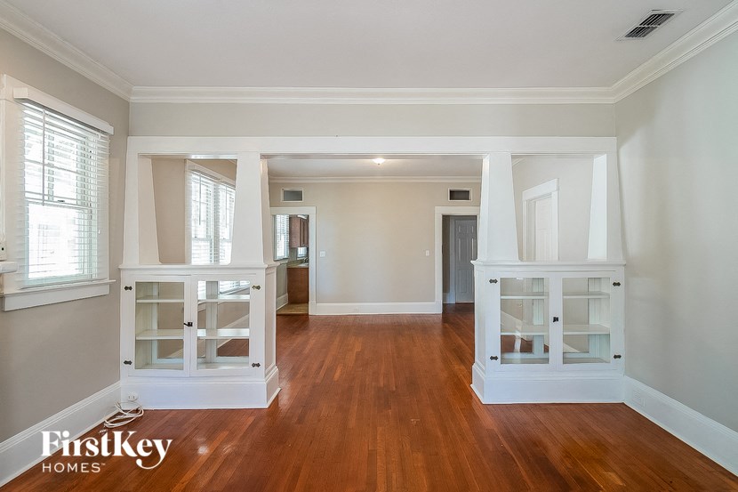 the living room and dining room of an empty house with wooden floors and white furniture