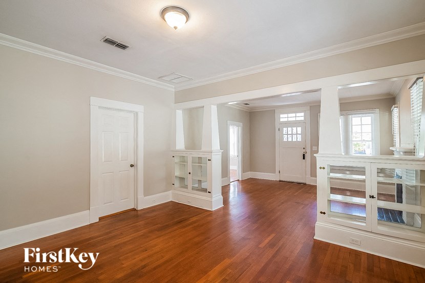 an empty living room with a wooden floor and white furniture