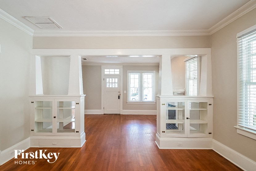 an empty living room with white shelves and a wood floor